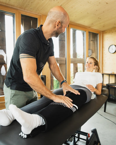 Physiotherapeut bringt Cryo Pro Manschetten bei Patientin an – gezielte Kryotherapie mit Kompression zur Regeneration in der Praxis.