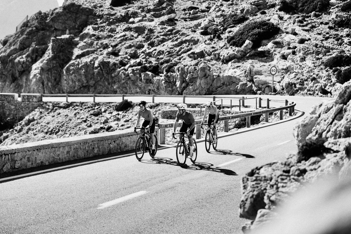 Gruppe von Rennradfahrern auf kurviger Küstenstraße beim Radtraining in den Bergen