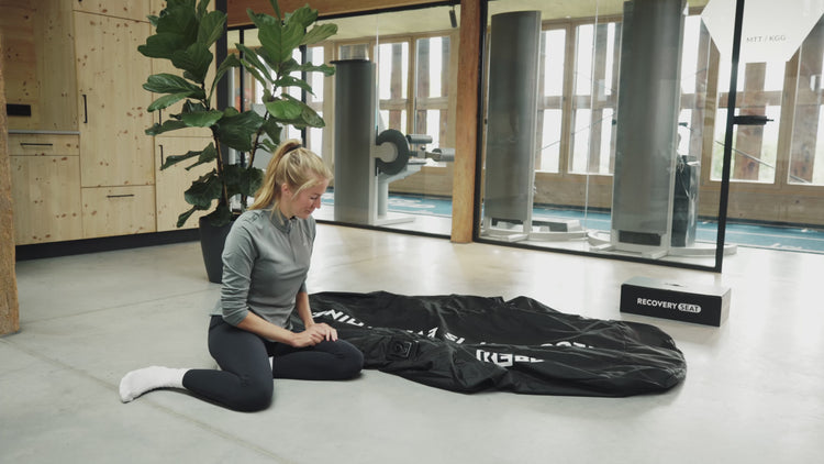 Reboots: Athletin kniet neben Kompressionsmassagegerät