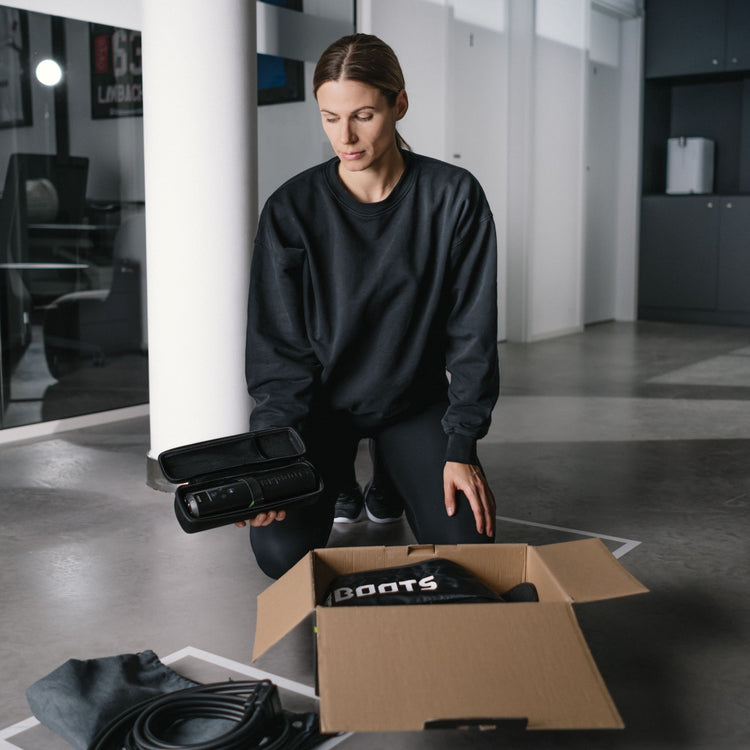 Reboots: Frau kniet und öffnet eine Packung GO LITE Sport-Drucktherapie.